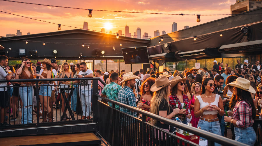 Rooftop do Vila 567 lotado no pôr do sol, com público sertanejo e skyline de SP